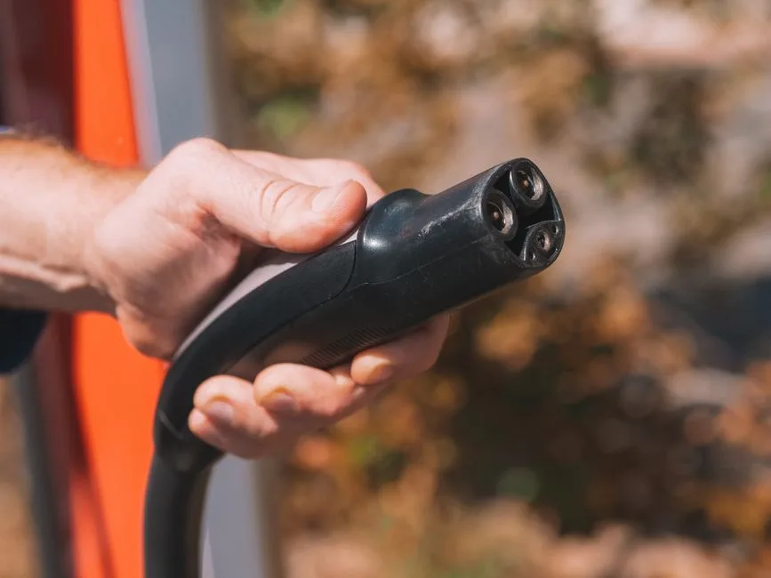 Main tenant une prise de recharge de véhicule électrique, illustrant une prise renforcée