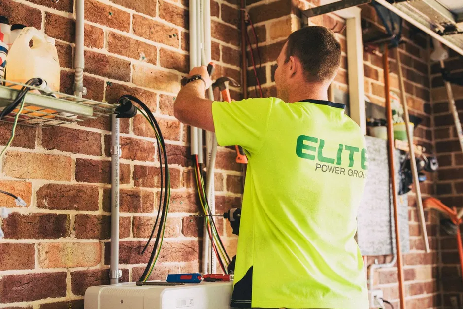Électricien installant un câble d'alimentation de borne sur un mur en briques